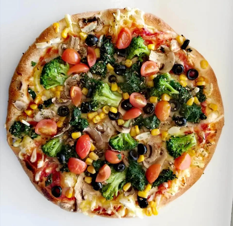 Pizza z brokułami, szpinakiem, pomidorkami cherry, czarnymi oliwkami, kukurydzą i pieczarkami