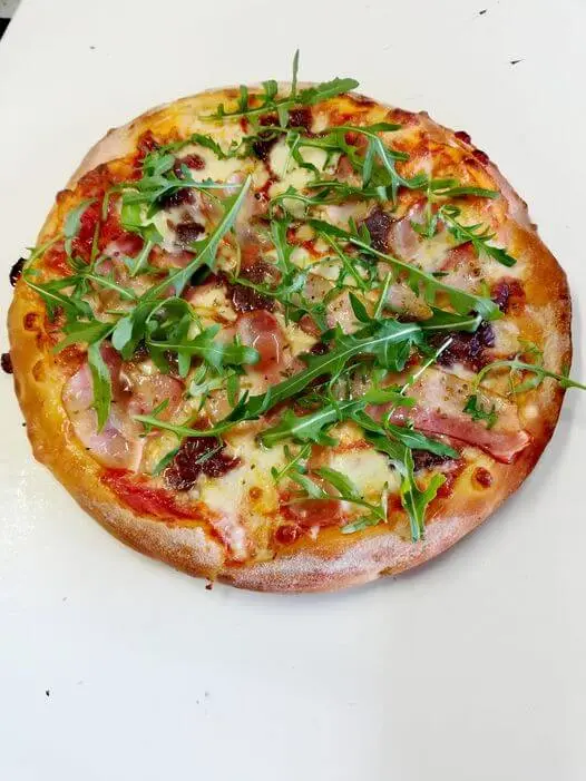 Pizza z szynką, suszonymi pomidorami i rukolą