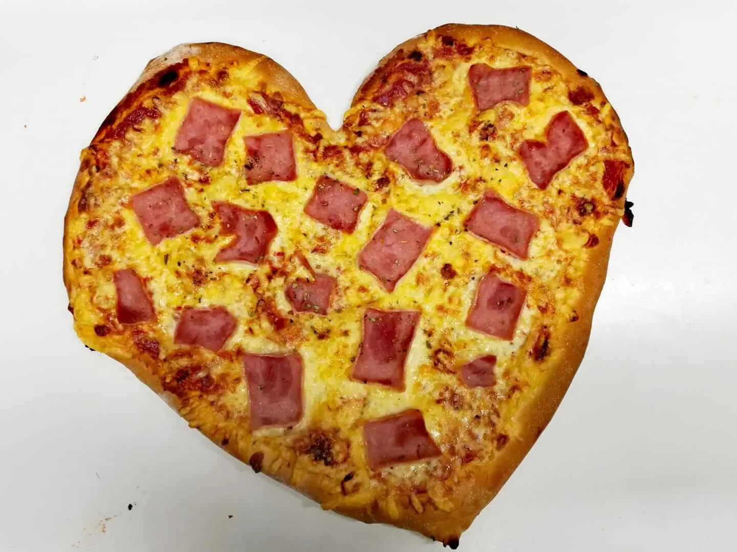 Pizza w kształcie serca z serem i kawałkami szynki