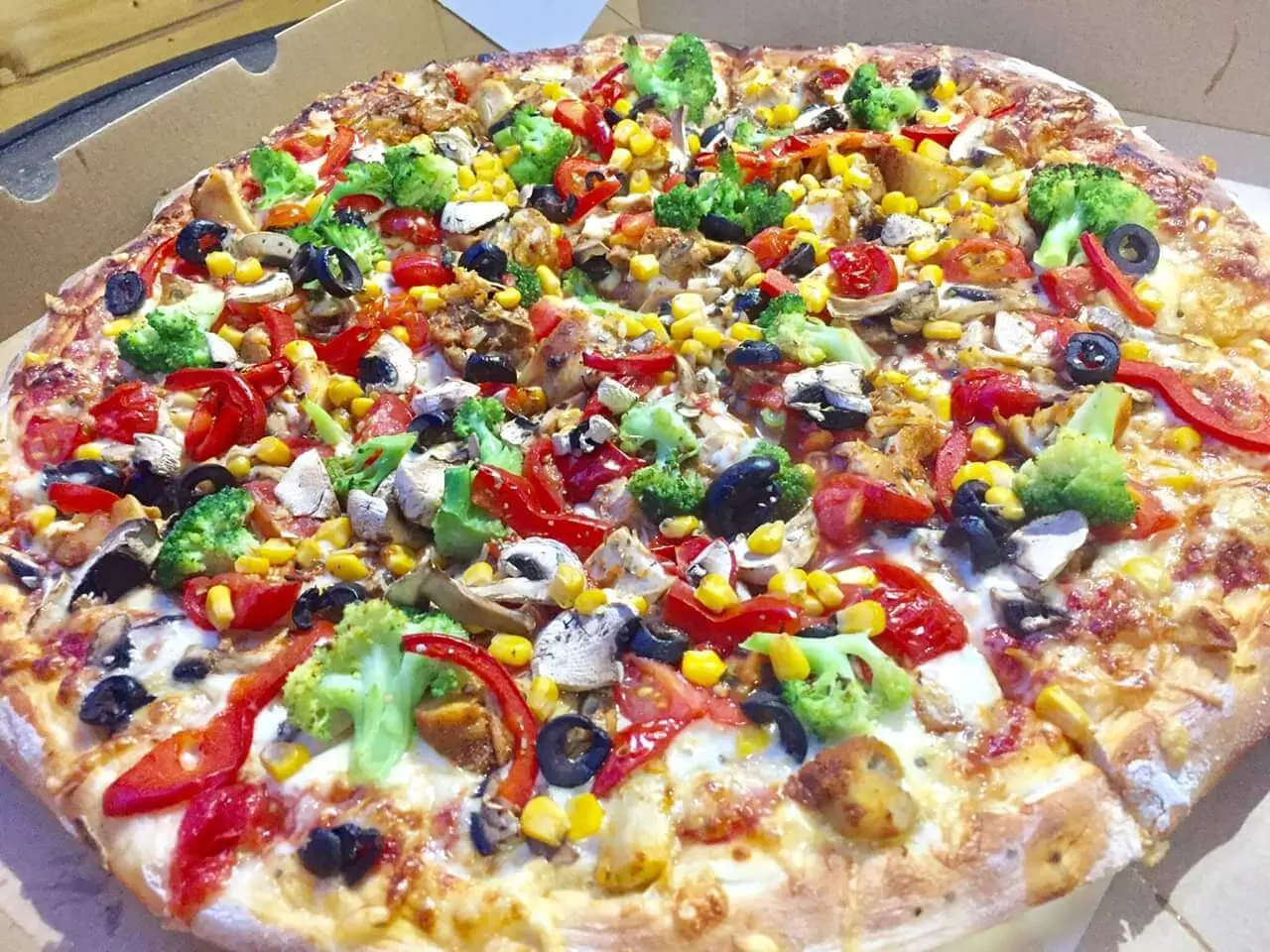Pizza z kurczakiem, brokułami, papryką, kukurydzą, pieczarkami i czarnymi oliwkami w pudełku