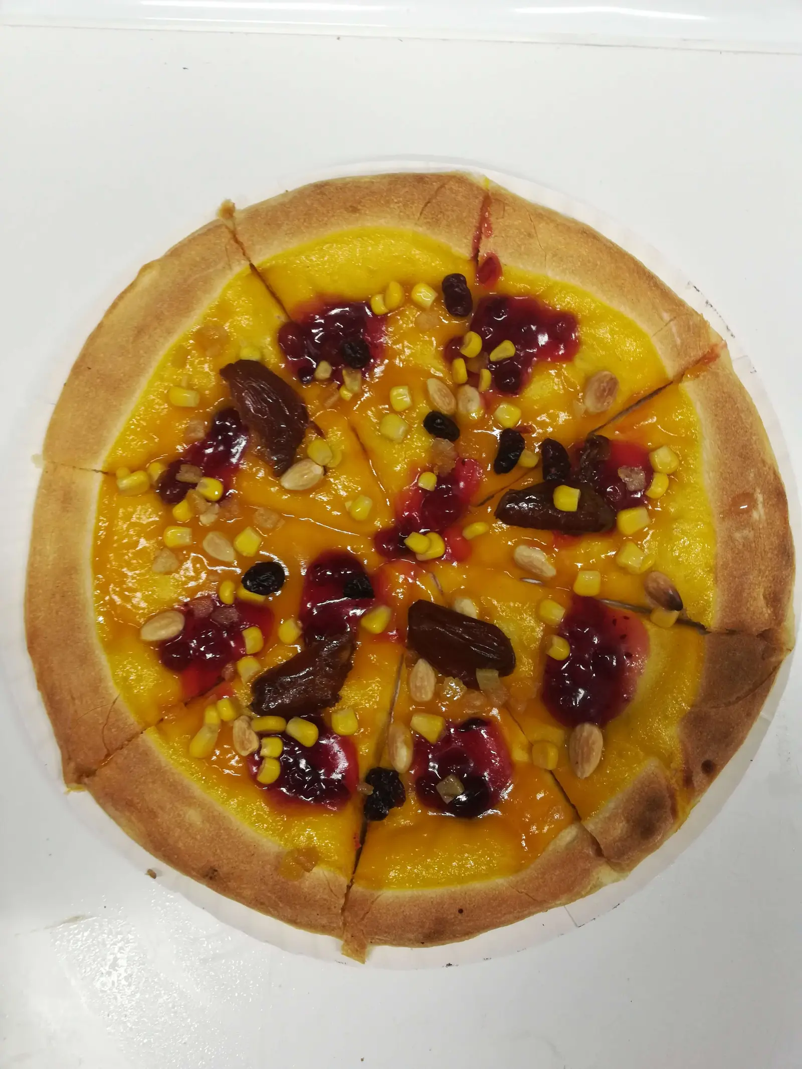 Pizza na żółtym sosie z kukurydzą, migdałami, rodzynkami, daktylami i czerwonym sosem owocowym